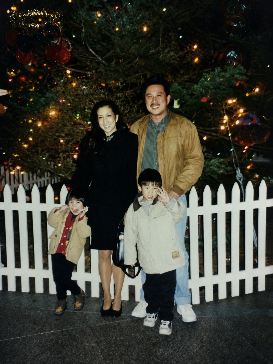 Joanne, Mel, and the two children in front of a Christmas tree, 1990s